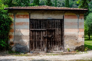 Beyaz ve turuncu çizgili taş duvarlı kadim alet kulübesi, antik ahşap kapı ve turuncu kiremit çatı