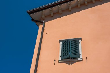 Pencereli ve yeşil balkonlu ev cephesi çağdaş mimari mavi gökyüzüne karşı duruyor