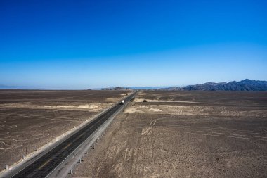 Asfalt yolu, Nazca Peru 'daki kahverengi çölde düz bir siyah katran çizgisi gibi çölden geçer.