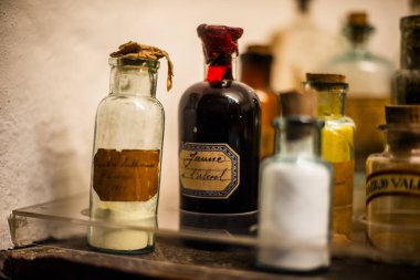 Peru 'nun dağlık bölgelerindeki Cuzco İnka şehrinde antik kahverengi yazıtlarla dolu vitrin şişelerinin arkasındaki eski ilaç şişeleri.