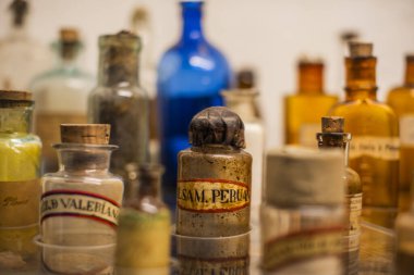 Peru 'nun dağlık bölgelerindeki Cuzco İnka şehrinde antik kahverengi yazıtlarla dolu vitrin şişelerinin arkasındaki eski ilaç şişeleri.