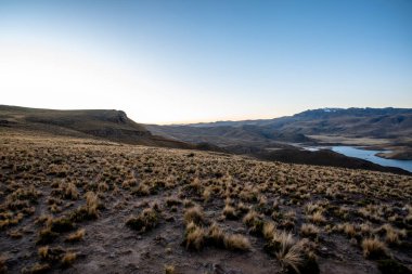 Umayo Gölü 'nün panoraması ve And Dağları' nın And Dağları manzaralı ve Peru 'nun dağlık bölgelerindeki güneşte kavrulmuş çalıları ile Titicaca Gölü' nün Puno köyündeki otlaklar.