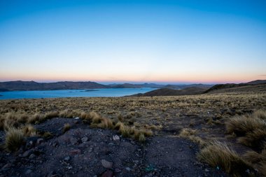 Umayo Gölü 'nün panoraması ve And Dağları' nın And Dağları manzaralı ve Peru 'nun dağlık bölgelerindeki güneşte kavrulmuş çalıları ile Titicaca Gölü' nün Puno köyündeki otlaklar.