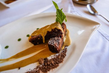 Tuzlu karamelli çikolatalı kek, beyaz tabak yeşil nane yaprağı.