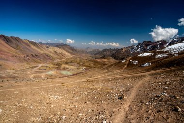 Peru 'nun Cusco bölgesinde, Ausangate yakınlarındaki Peru Andean dağlarında, arka planda platoda mavi gökyüzü ve beyaz bulutlar bulunan tepe ve vadi manzaraları.