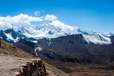 Peru 'nun Cusco bölgesinde, Ausangate yakınlarındaki Peru Andean dağlarında, arka planda platoda mavi gökyüzü ve beyaz bulutlar bulunan tepe ve vadi manzaraları.