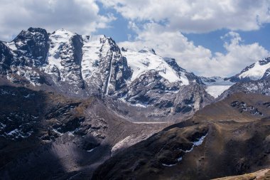 Peru 'nun Cusco bölgesinde, Ausangate yakınlarındaki Peru Andean dağlarında, arka planda platoda mavi gökyüzü ve beyaz bulutlar bulunan tepe ve vadi manzaraları.