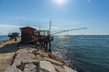 Veneto İtalya 'daki Venice Lido' daki Murazzi 'nin yanındaki Malamocco yakınlarındaki liman barajlarında balık tutmak için ağları olan eski ahşap ve demir balıkçı kulübeleri.