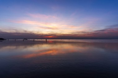 Venedik gölünün sakin sularına kırmızı ve turuncu renklerle yanan günbatımı yansıtılır. Venedik 'teki Venedik Lido' sundan çekilen tuğla ve ağaçlarla.