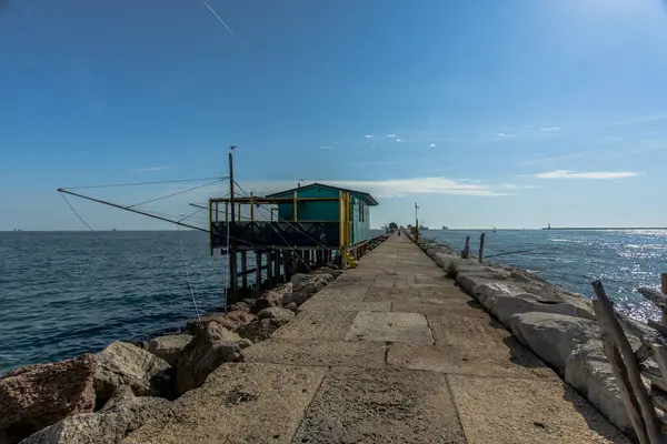 Veneto İtalya 'daki Venice Lido' daki Murazzi 'nin yanındaki Malamocco yakınlarındaki liman barajlarında balık tutmak için ağları olan eski ahşap ve demir balıkçı kulübeleri.