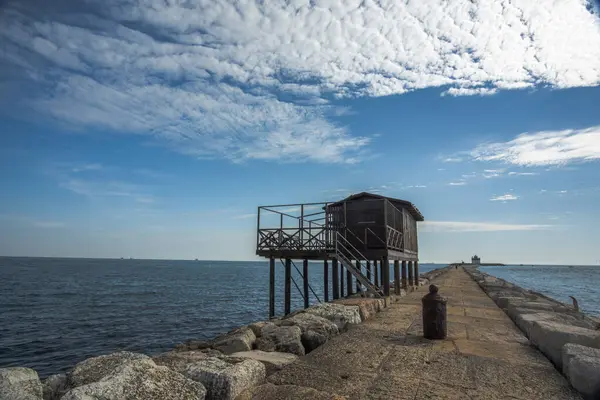 Veneto İtalya 'daki Venice Lido' daki Murazzi 'nin yanındaki Malamocco yakınlarındaki liman barajlarında balık tutmak için ağları olan eski ahşap ve demir balıkçı kulübeleri.