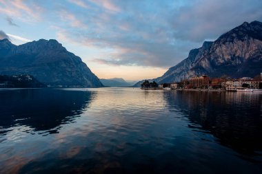 Sonbaharda Lecco Gölü 'nün sakin ve sakin sularıyla gün batımının olduğu bir akşam İtalya' nın Lecco kentindeki dağların arasında.