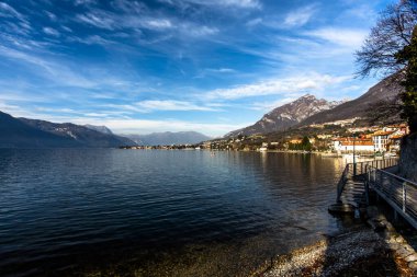 Sonbaharda Lecco Gölü 'nün sakin ve sakin sularıyla gün batımının olduğu bir akşam İtalya' nın Lecco kentindeki dağların arasında.