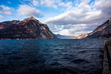 Sonbaharda Lecco Gölü 'nün sakin ve sakin sularıyla gün batımının olduğu bir akşam İtalya' nın Lecco kentindeki dağların arasında.