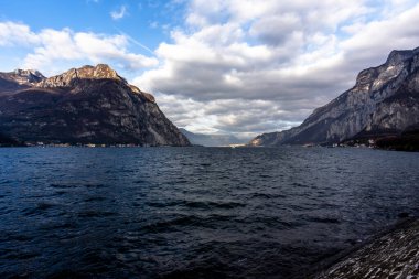 Sonbaharda Lecco Gölü 'nün sakin ve sakin sularıyla gün batımının olduğu bir akşam İtalya' nın Lecco kentindeki dağların arasında.