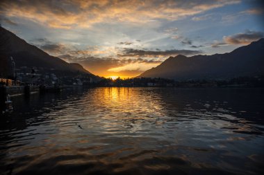 Sonbaharda Lecco Gölü 'nün sakin ve sakin sularıyla gün batımının olduğu bir akşam İtalya' nın Lecco kentindeki dağların arasında.