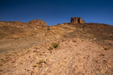 panorama of volcanic mountains and plains and plateaus the peaks and rocks of the south atlas morocco on the atlas between Bab N Ali and Jebel Saghro near Marrakesh and Ouarzazate in Morocco clipart