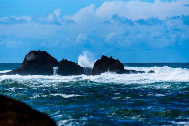 Okyanus dalgaları gün batımında Fas 'taki Essaouira adalarında kayalara çarpar.