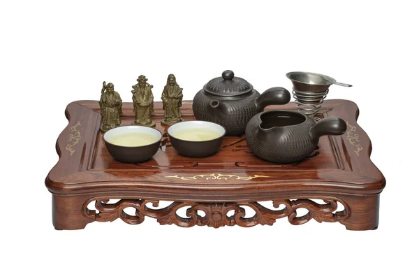 Wooden Chinese tea table Chaban with a set of dishes for tea drinking and three brass figurines of the elders Fuk, Luk and Sa, on a white background.
