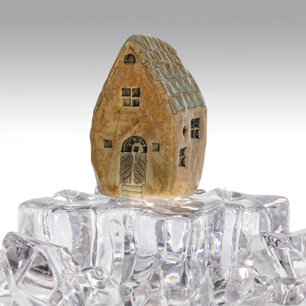A handmade ceramic house on ice cubes, taken in close-up.