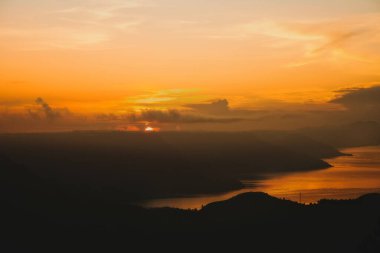 Toba Gölü üzerinde Altın Gün Doğumu bu büyüleyici fotoğraf Sumatra, Endonezya 'da Toba Gölü üzerinde altın bir gündoğumu görüntüler. Sakin sular ve bereketli tepeler, nefes kesici bir manzara arayan doğa ve seyahat meraklıları için mükemmel sakin bir manzara yaratır..