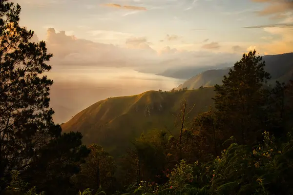 stock image Golden Sunrise Over Lake TobaThis captivating photo captures a golden sunrise over Lake Toba in Sumatra, Indonesia. The serene waters and lush hills create a tranquil scene, perfect for nature and travel enthusiasts seeking a breathtaking view.