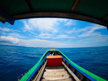 Idyllic Tekne Yolculuğu Sumatra 'nın Mavi Suları. Sumatra 'nın dingin güzelliğini, parlak, açık bir gökyüzünün altında kristal berrak mavi sularda süzülen geleneksel bir tekneden deneyimleyin. Seyahat ve macera temaları için mükemmel.