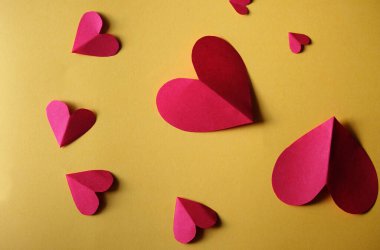 Sarı arkaplanda kırmızı kağıt kalpler grubu - Sevgililer Günü konsepti