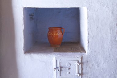 red clay pot on old rustic wood stove in historic farmhouse in Poland