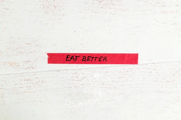 motivational ;eat better\' message handwritten on colorful washi tape against white wooden background