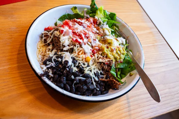 taco bowl with meat, black beans, tomato salsa and rice as served at mexican fast food restaurant