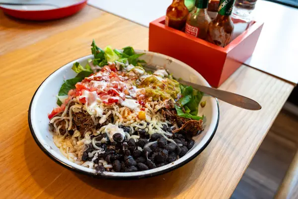 taco bowl with meat, black beans, tomato salsa and rice as served at mexican fast food restaurant