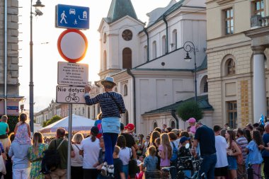 Lublin, Polonya 26 Temmuz 2024 'te bir sokak sanatçısı sirk sokak festivalini izlemek için diğer izleyicilerin üzerinde duran şapkalı bir adam.