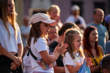 Lublin, Polonya, 26 Temmuz 2024 bir sokak sirki festivali ('Carnavl Sztukmistrzow') seyircileri arasında gün batımında ellerini çırpıyor