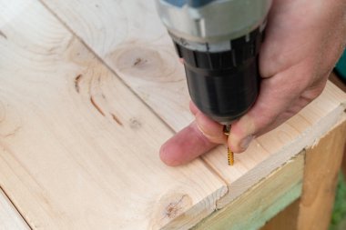 Tahta bir tahtayı vida tabancasıyla ahşap bir çerçeveye vidalayarak basit bir masayı diy projesi yapmak.