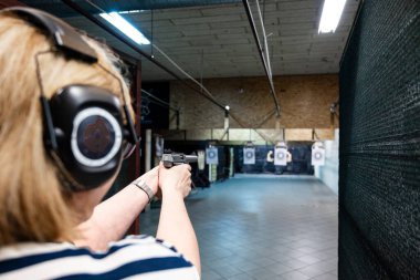 Kadın atış poligonuna silahla nişan alıyor.