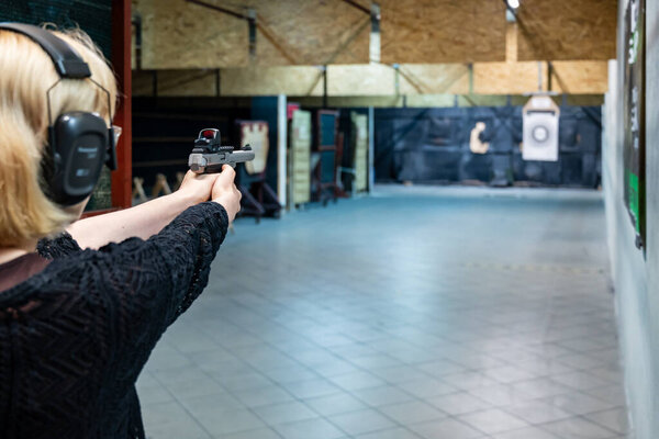 woman aims at a target with a pistol at a shooting range