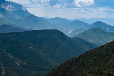 Vercors 'ta, Fransa' da Alpler öncesi bölgede, dağların tepeleri ve beyaz bulutların mavi gökyüzüne karşı güzel bir manzarası.