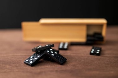 Tahta bir masada bir kutu domino taşı.