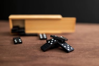 Tahta bir masada bir kutu domino taşı.