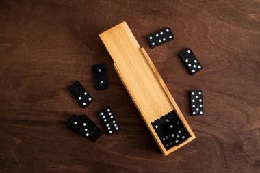 Tahta bir masada bir kutu domino taşı.