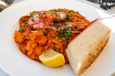 bir tabak geleneksel İspanyol yemeği - karides, pirinç, kalamar, midye ve sebzeli deniz ürünleri paella limon, safran ve taze ekmekle servis edilir.