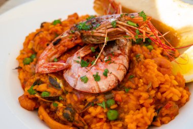 bir tabak geleneksel İspanyol yemeği - karides, pirinç, kalamar, midye ve sebzeli deniz ürünleri paella limon, safran ve taze ekmekle servis edilir.
