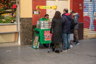 Malaga, İspanya, 29 Aralık 2024 Bir sokak satıcısından piyango bileti almak için kuyruğa girdi