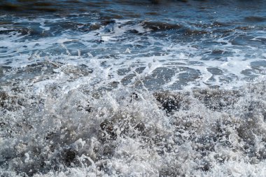 Deniz kıyısına çarpan bir dalgada oluşan beyaz köpük yakın plan - doğal dinamik arkaplan