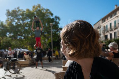 Genç bir kadın güneşli bir günde Malaga, İspanya 'da sokak akrobatlarının sirk performansına hayran.