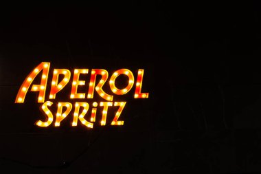 Malaga, İspanya, 28 Aralık 2024 Siyah zemin üzerinde Aperol Spritz alkol reklamı yazan parlak neon tabela