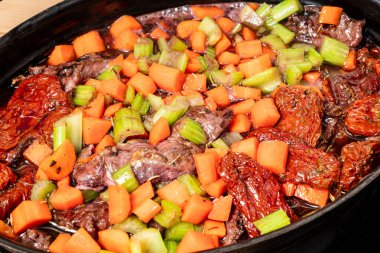 the preparation of beef cheeks sauteed in rich wine rosemary and vegetable gravy clipart