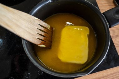 Çikolata jölesi yapmak için tereyağını sıcak tavada eritiyorum.