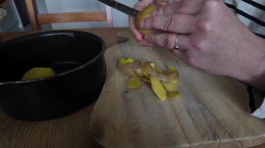 Kadın evde bıçakla patates soyuyordu.
